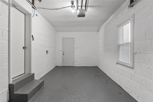 garage featuring concrete block wall and a garage door opener