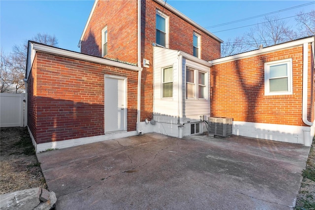 back of house with central air condition unit, fence, and brick siding