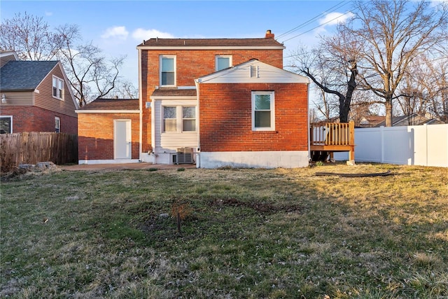 rear view of house with brick siding, a lawn, cooling unit, a chimney, and a fenced backyard