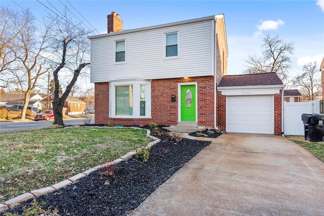 colonial home with driveway, fence, an attached garage, brick siding, and a chimney