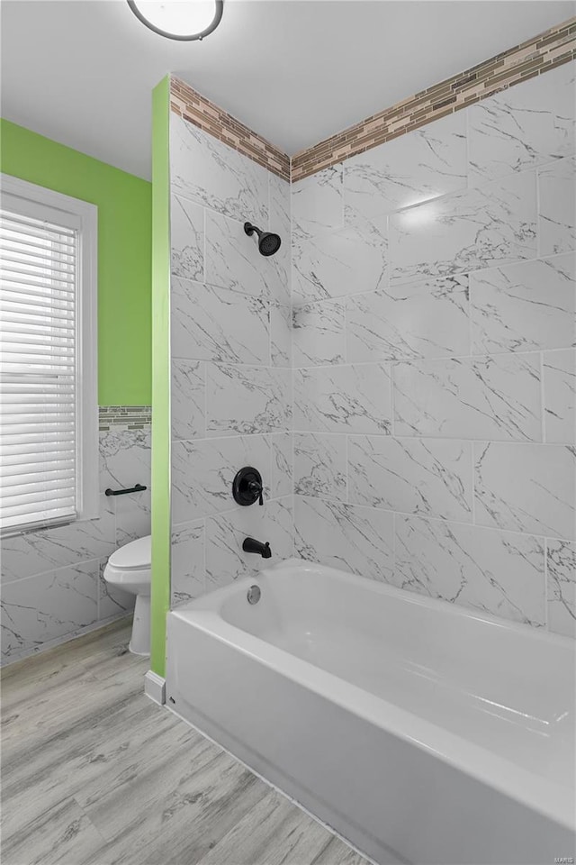 full bathroom with toilet, tile walls, and  shower combination