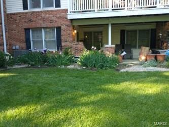 back of house featuring a lawn and brick siding