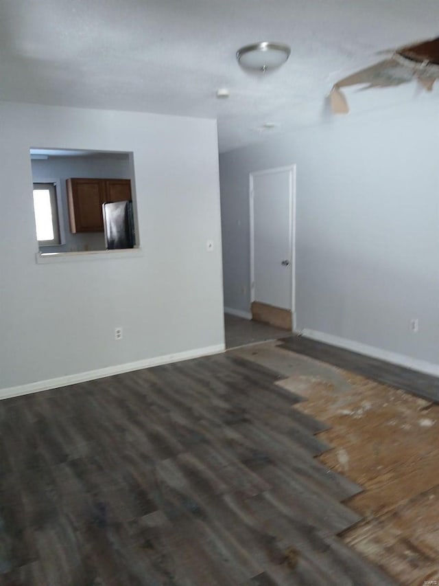 empty room featuring baseboards and dark wood-style floors