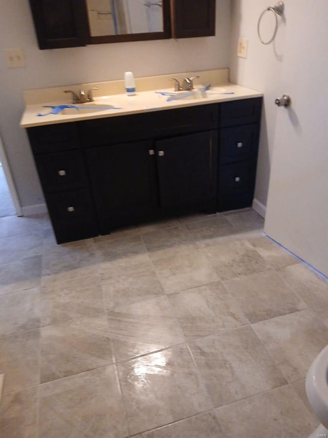 full bath featuring a sink, baseboards, and double vanity