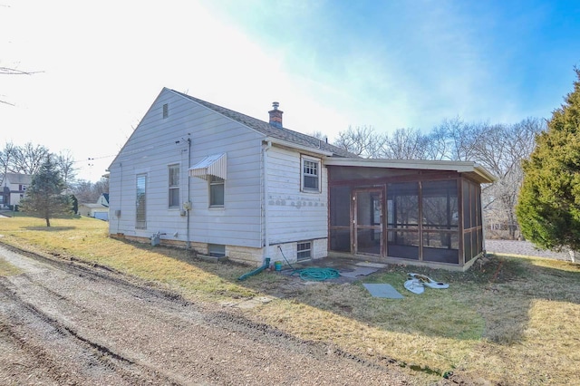 back of property featuring a lawn, a sunroom, and a chimney