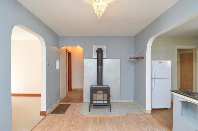 room details featuring a wood stove, wood finished floors, baseboards, and freestanding refrigerator