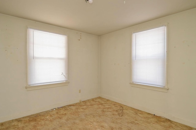 empty room featuring baseboards and light colored carpet