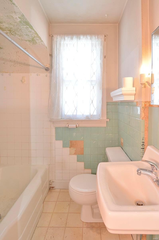 bathroom with toilet, a sink, tile walls, wainscoting, and tile patterned flooring