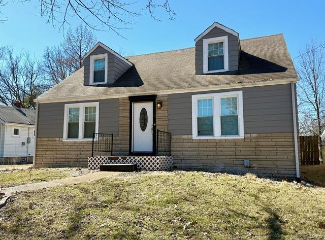 view of front of home with stone siding and a front lawn