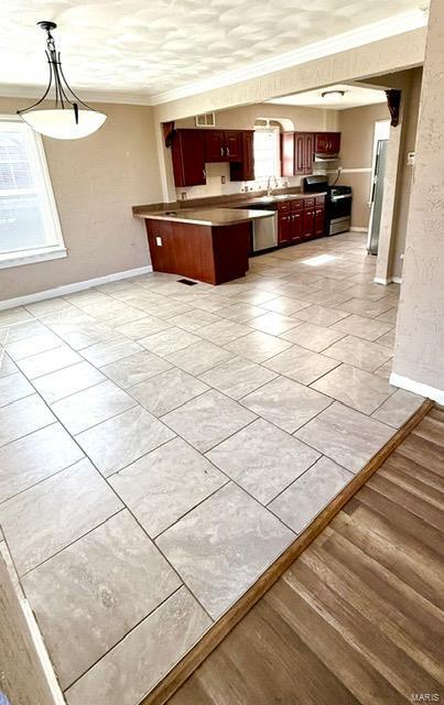 kitchen featuring open floor plan, stainless steel appliances, a peninsula, baseboards, and dark brown cabinets