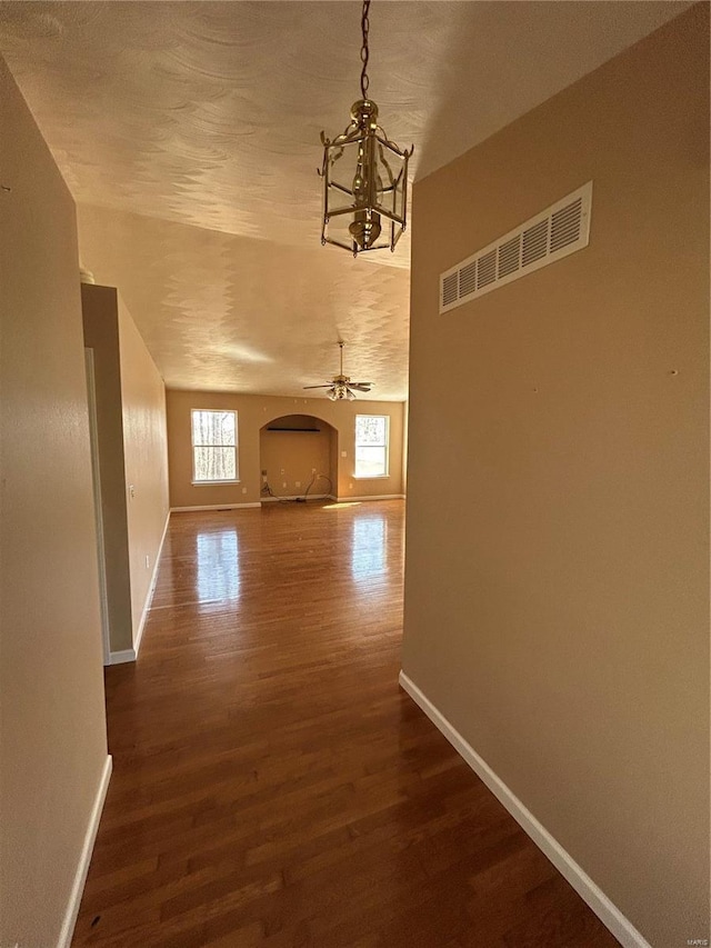 corridor featuring visible vents, baseboards, dark wood-style floors, and a chandelier