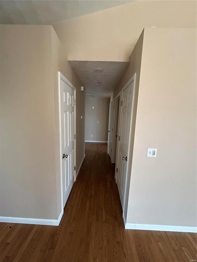 corridor with baseboards and wood finished floors