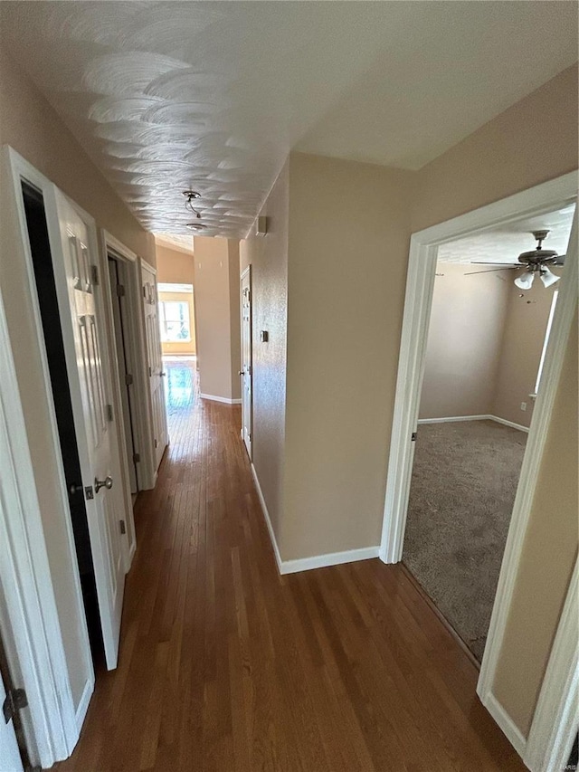 hall with baseboards and wood finished floors