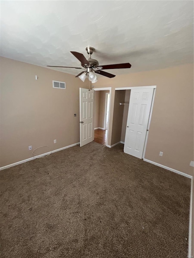 empty room with baseboards, visible vents, dark carpet, and ceiling fan