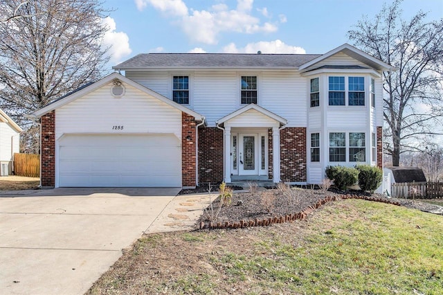 traditional home featuring brick siding, an attached garage, driveway, and fence