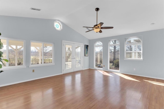 unfurnished living room with wood finished floors, visible vents, baseboards, lofted ceiling, and french doors