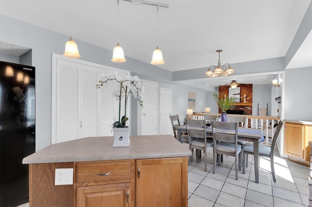 kitchen featuring a kitchen island, pendant lighting, ceiling fan with notable chandelier, freestanding refrigerator, and light tile patterned flooring