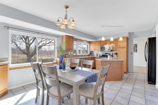 dining room with light tile patterned floors, baseboards, an inviting chandelier, and rail lighting