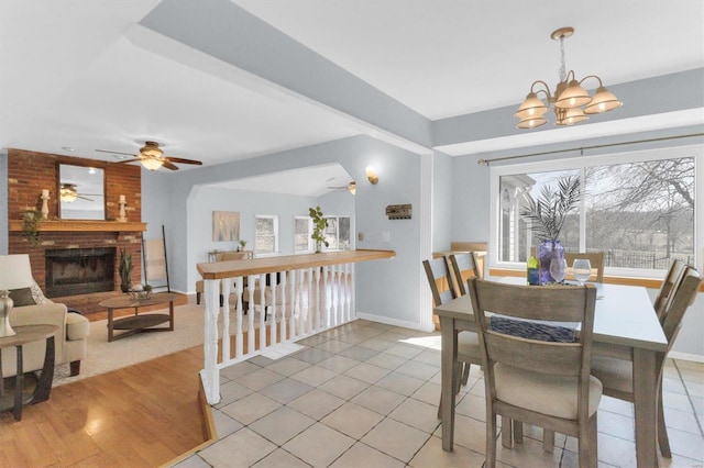 dining space with a chandelier, light tile patterned floors, a healthy amount of sunlight, and a fireplace