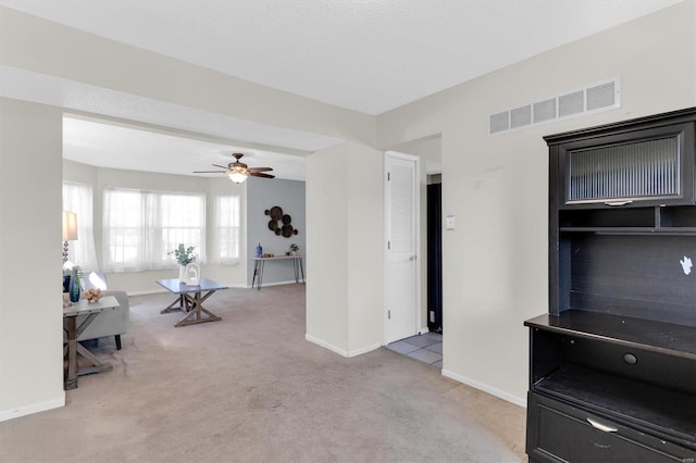 living area with visible vents, light carpet, baseboards, and a ceiling fan