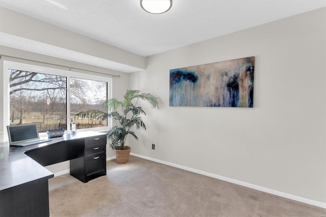 home office featuring light colored carpet, a textured ceiling, and baseboards