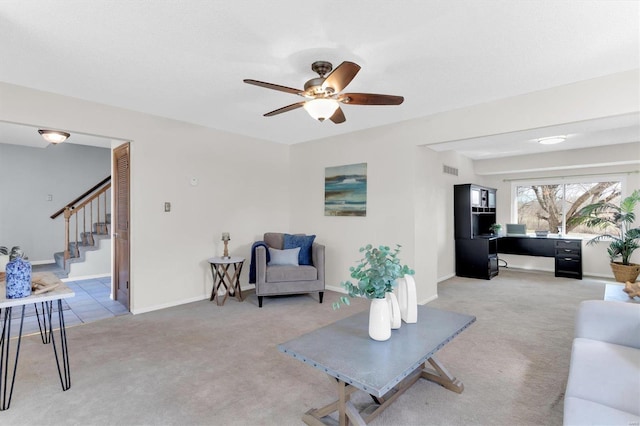 living room featuring visible vents, stairway, baseboards, light colored carpet, and ceiling fan