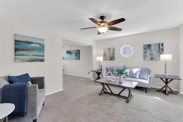 carpeted living room with baseboards, a textured ceiling, and ceiling fan