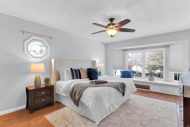 bedroom with wood finished floors, visible vents, and a textured ceiling