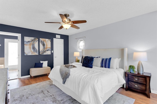 bedroom with a ceiling fan, multiple windows, wood finished floors, and a textured ceiling