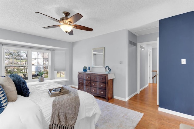 bedroom with a ceiling fan, wood finished floors, baseboards, and a textured ceiling