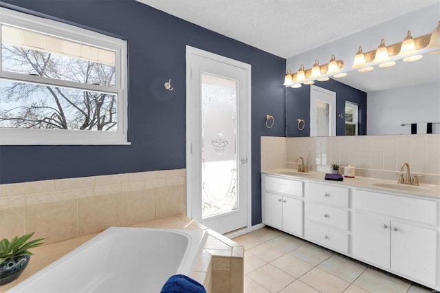 bathroom featuring tile patterned flooring, double vanity, a bath, and a sink