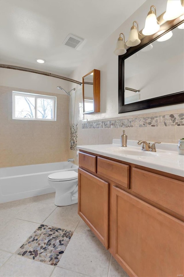 full bath featuring tile patterned floors, visible vents, toilet, tile walls, and shower / bathtub combination