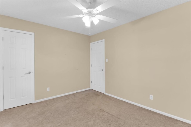 carpeted spare room with a ceiling fan and baseboards