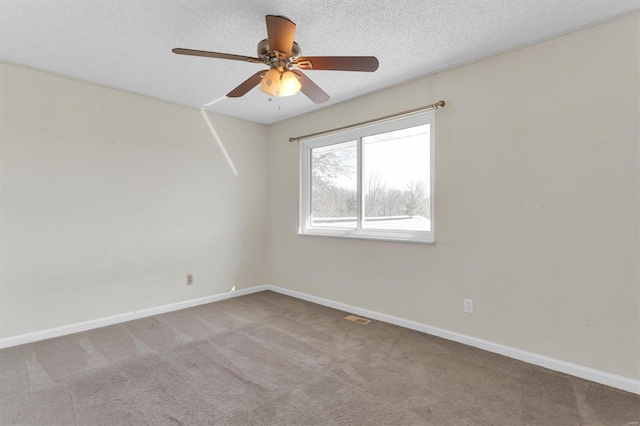 spare room featuring baseboards, visible vents, carpet floors, ceiling fan, and a textured ceiling