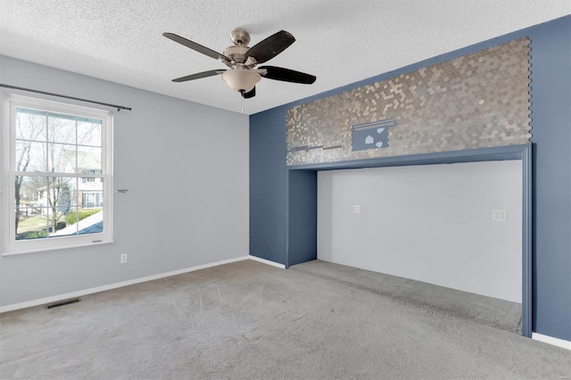 spare room with a ceiling fan, visible vents, carpet floors, and a textured ceiling