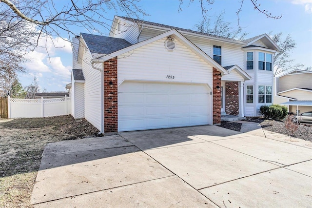 traditional-style home featuring fence, an attached garage, a shingled roof, concrete driveway, and brick siding