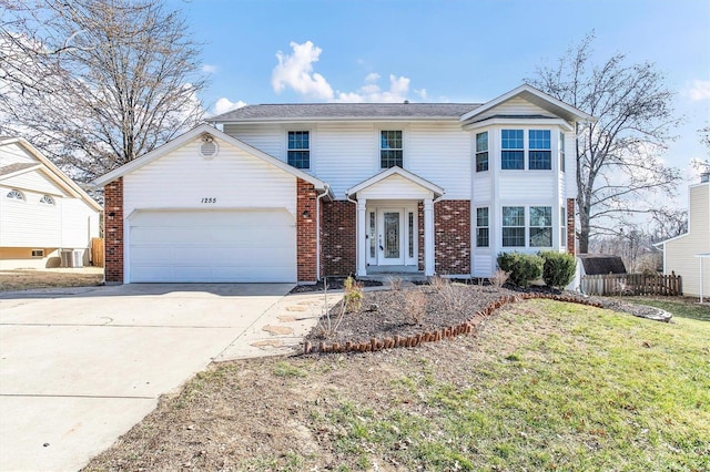 traditional home with brick siding, a front lawn, fence, driveway, and an attached garage