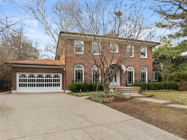 colonial home featuring brick siding, an attached garage, and driveway