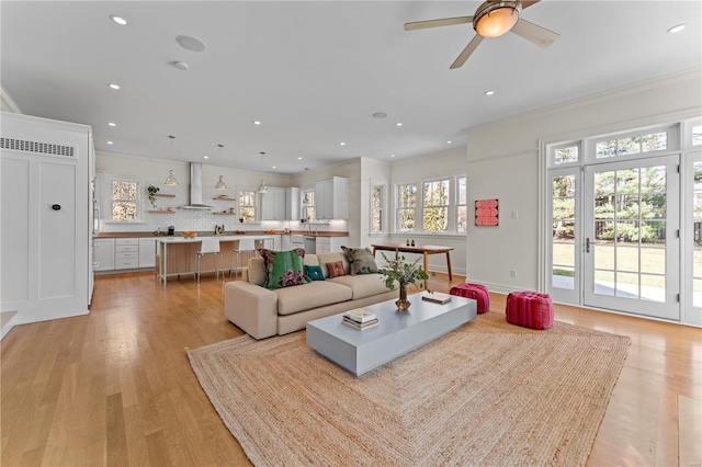 living room with recessed lighting, light wood-type flooring, ceiling fan, and ornamental molding