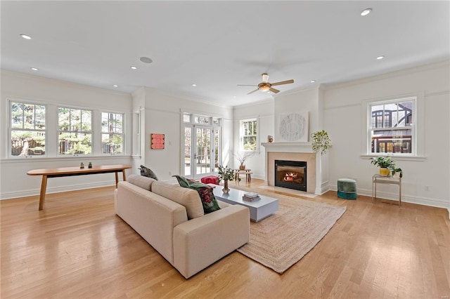 living room with crown molding, baseboards, a fireplace with flush hearth, recessed lighting, and light wood-style floors