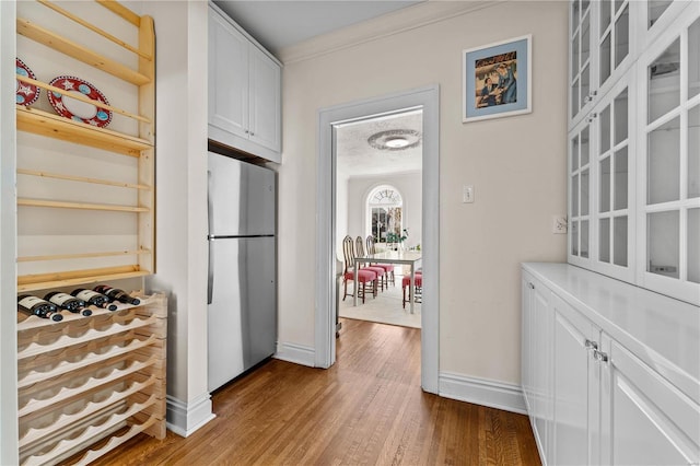 kitchen featuring baseboards, white cabinets, dark wood-style flooring, and freestanding refrigerator