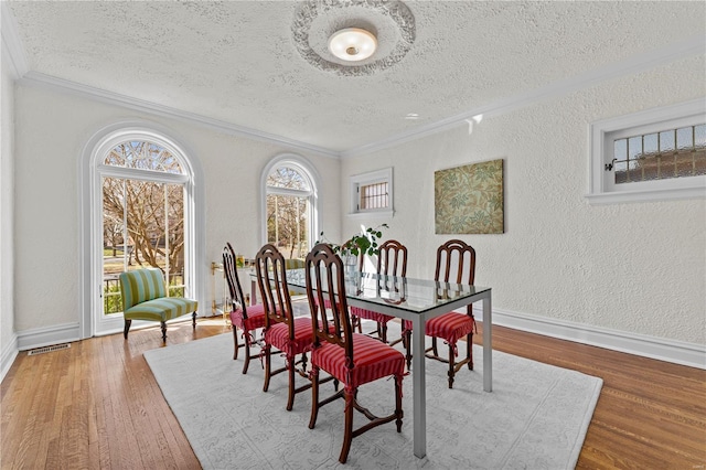 dining space featuring a textured ceiling, wood finished floors, and a textured wall