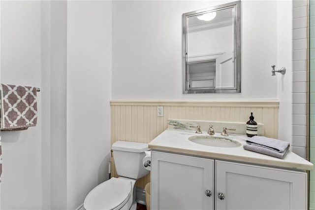 bathroom featuring vanity, toilet, and wainscoting