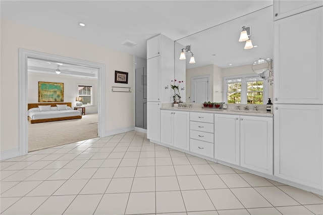 bathroom with a sink, ensuite bath, double vanity, and tile patterned floors