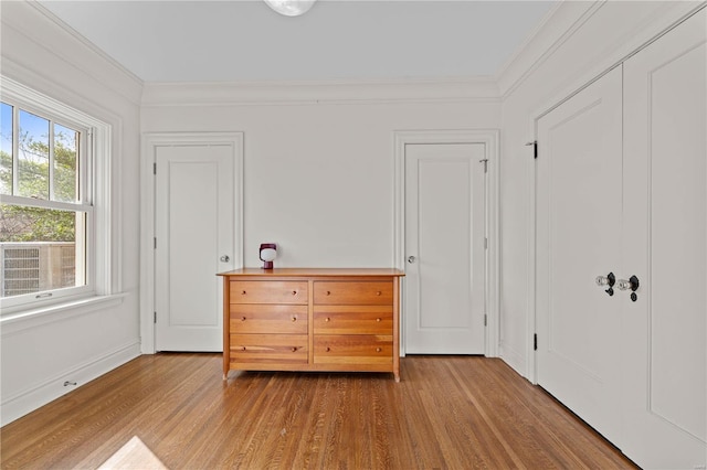 unfurnished bedroom with crown molding, wood finished floors, and baseboards