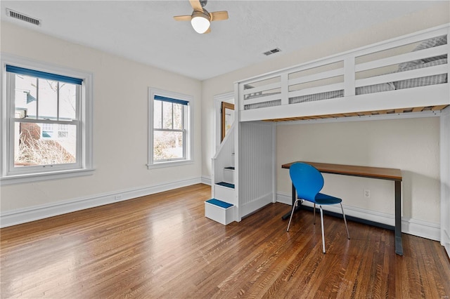 unfurnished bedroom with visible vents, a ceiling fan, baseboards, and wood finished floors