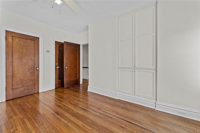 unfurnished bedroom featuring ceiling fan, baseboards, and wood finished floors