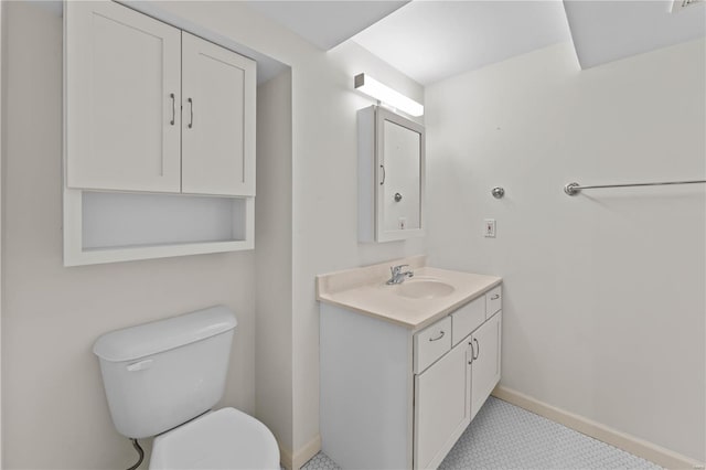 half bathroom featuring toilet, vanity, and baseboards