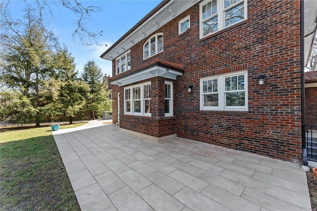 rear view of property with a yard, a patio, and brick siding