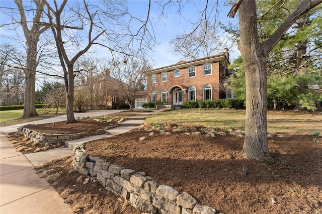 colonial inspired home with a front lawn, brick siding, and a chimney